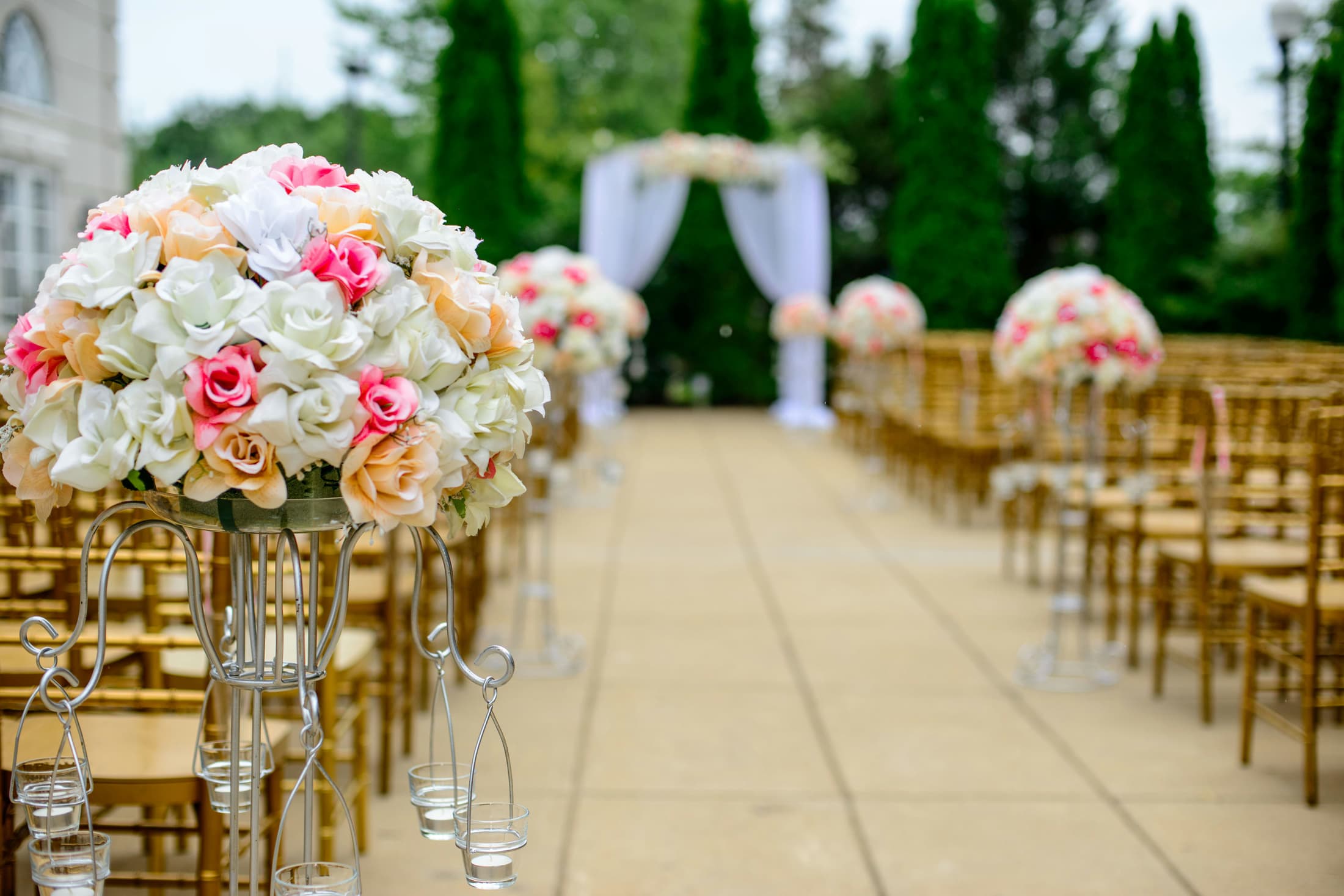 Allée de cérémonie bordée de roses menant à une arche de mariage